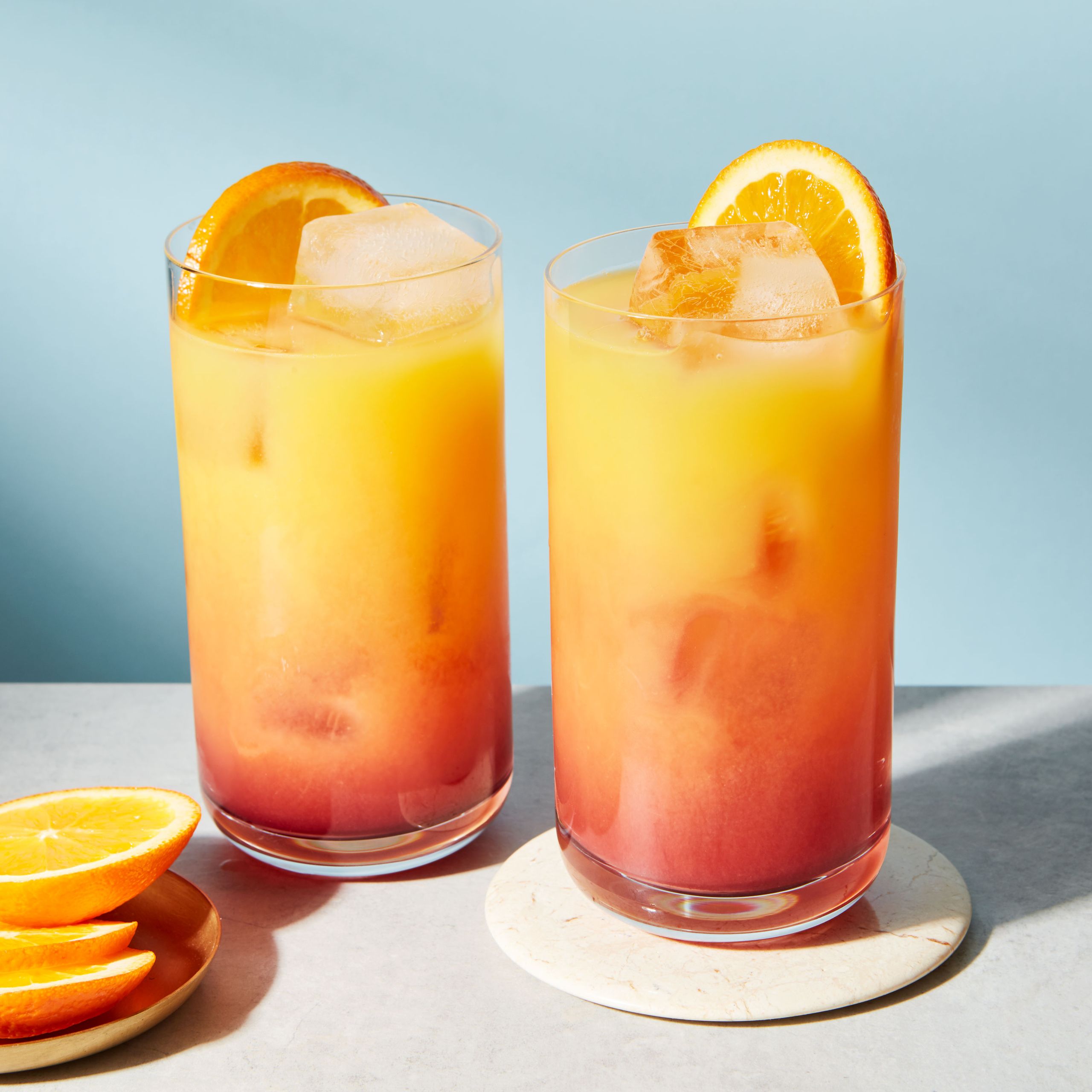 Tequila Sunrise variations with modern garnishes: dehydrated fruit, edible flowers, & ice.
